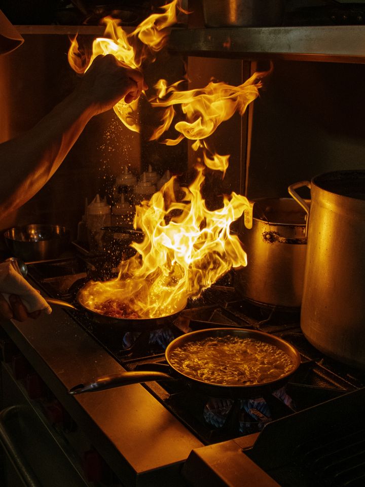 A cook flambeing a pan on the line in the Restaurante Bocas kitchen