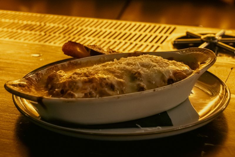 Ropa vieja mac and cheese gratinated in an oval dish, served at the bar