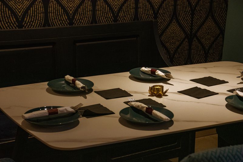 A marble table laid with teal plates, folded napkins and a gold candle at Restaurante Bocas