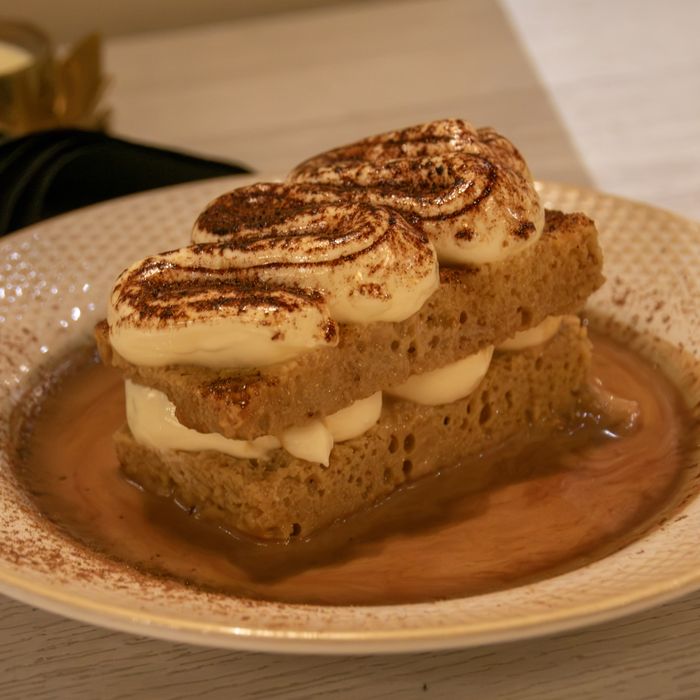 A layered sponge dessert with whipped cream and dusted cinnamon in caramel sauce at Restaurante Bocas