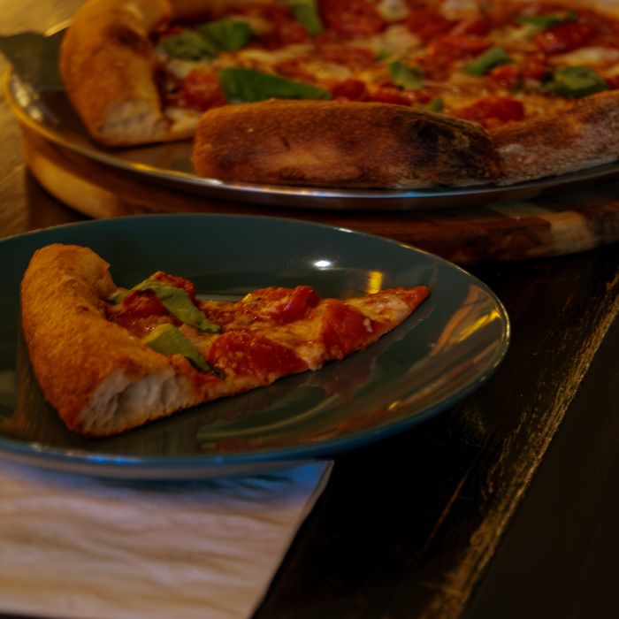 A Napolitano margherita pizza at Restaurante Bocas, a slice served on a blue plate at the bar